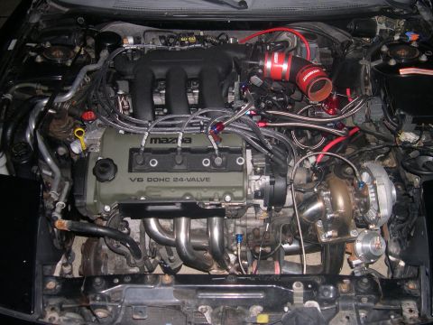 1997 Ford Probe - Engine bay view of a modified Mazda V6 engine a turbocharger and custom exhaust manifold.