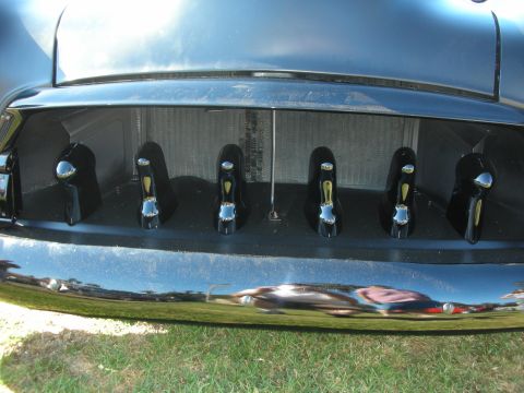 1998 Ford Crown Victoria - Close-up of an open custom trunk revealing two rows of chrome-handled levers above a chrome bumper, reflecting the grass.