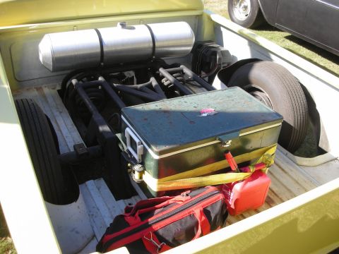 1998 Ford Crown Victoria - bed of a yellow custom pickup opened to reveal a polished air tank, metal toolbox, red bags and the exposed rear chassis.