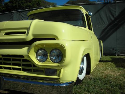 1998 Ford Crown Victoria - Close front three-quarter view of a yellow custom Ford pickup with dual round headlights, chrome bumper and whitewall tires, body slammed l…
