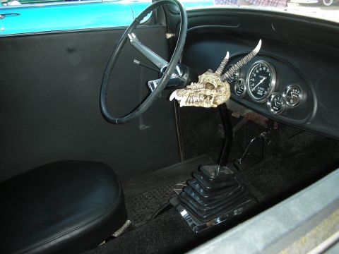 1998 Ford Crown Victoria - Spartan hot rod cabin with a bench seat, black steering wheel, classic round gauges and a horned animal-skull mounted on the tall shifter.