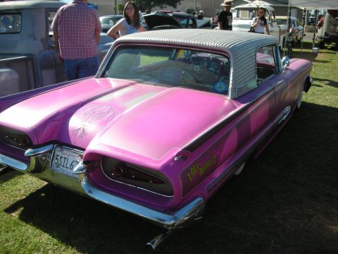 1998 Ford Crown Victoria - wild pink-and-purple custom Thunderbird with airbrushed graphics and a padded top, shown rear three-quarter on grass at a show.