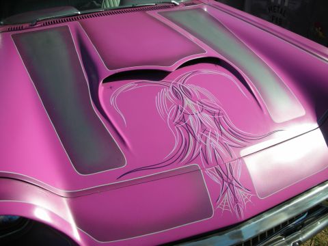 1998 Ford Crown Victoria - Close-up of a pink custom car hood scoop airbrushed with a flowing-hair figure, gray panels and a pinstriped spiderweb detail.