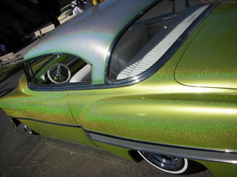 1998 Ford Crown Victoria - Detail shot of the swirling green metalflake paint, frenched side window and chrome rocker trim of a custom car.