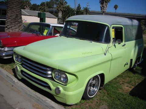 1998 Ford Crown Victoria - lime green lowered 1950s-style panel delivery truck with a two-tone roof sits beside a red car on chrome wheels.
