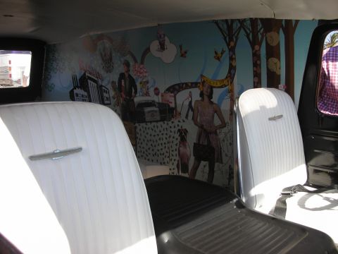 1998 Ford Crown Victoria - Interior of a custom van showing white pleated bucket seats and a brightly painted whimsical mural across the rear panel.