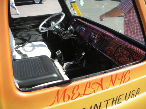 1998 Ford Crown Victoria - Interior of an orange custom truck with a pinstriped dash, white seat and MELANE / IN THE USA lettering painted on the door.