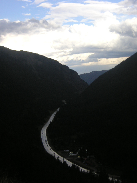 1996 Mazda Miata - A winding road cuts through a deep mountain valley under a dramatic sky.