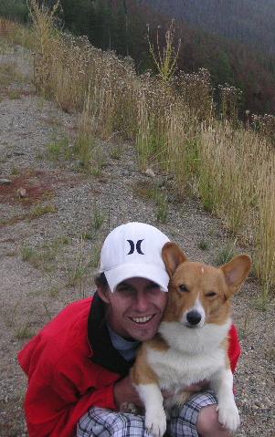 1996 Mazda Miata - A man and his corgi enjoy a moment together in an outdoor, grassy setting.