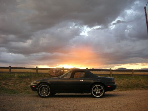 1996 Mazda Miata - Dark 1996 Mazda Miata parked on a gravel road during a dramatic sunset.