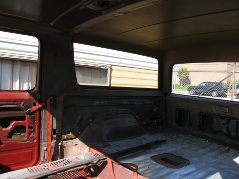 1986 Ford Bronco - Interior view of a stripped-down SUV, with a black SUV seen through the rear window.