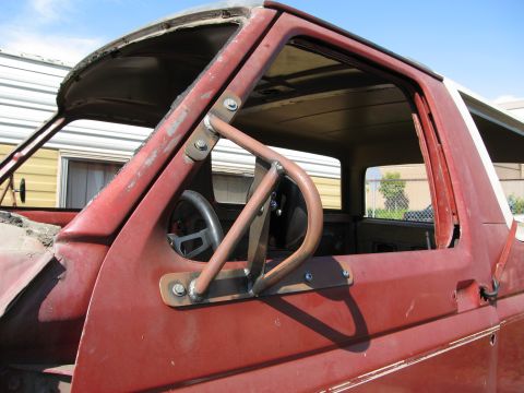 1986 Ford Bronco - Custom roll cage installed on the interior of a red vehicle's door frame.