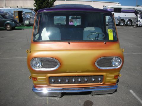1998 Ford Crown Victoria - Head-on view of a gold-to-orange custom van with mesh-covered round headlights and a row of bumper bullets in a lot.
