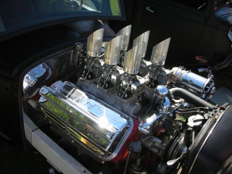1998 Ford Crown Victoria - chrome-dressed V8 with four tall ribbed velocity stacks and a Weiand-branded valve cover sits in a black hot rod engine bay.