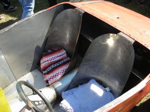 1998 Ford Crown Victoria - open cockpit of an orange hot rod shows two bare-metal bucket seats lined with a striped serape and blue towel.