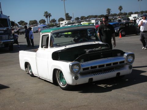1998 Ford Crown Victoria - slammed white classic pickup with green wheels and its hood removed sits in a paved lot among other show vehicles.