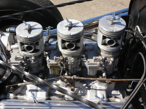 1998 Ford Crown Victoria - Detailed view of a triple-carburetor intake with finned tops mounted on an aluminum manifold of a hot rod engine.