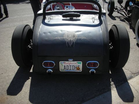 1998 Ford Crown Victoria - Rear view of a black hot rod roadster with pinstriping, dual exhaust, red interior and a California plate reading ADIOHS.