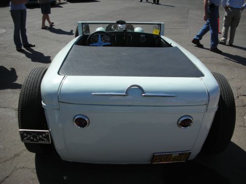 1998 Ford Crown Victoria - Rear view of a pale blue hot rod roadster with twin round taillights, smooth deck and a yellow California plate at a show.
