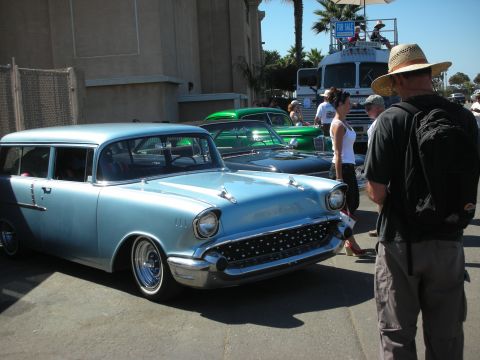 1998 Ford Crown Victoria - light blue custom 1950s Chevrolet two-door wagon with whitewalls and a man in a straw hat at an outdoor car show.