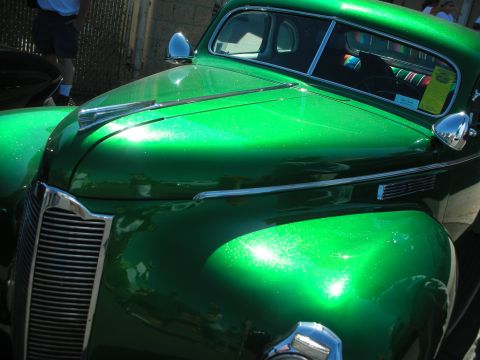 1998 Ford Crown Victoria - Close view of the metallic green hood, grille and chrome trim of a glossy vintage custom coupe in sunlight.