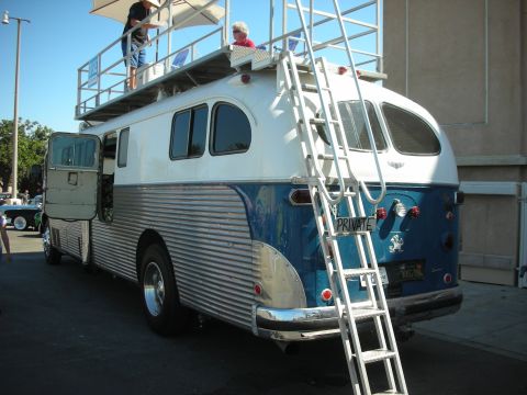 1998 Ford Crown Victoria - blue-and-white vintage bus converted into a camper, with a rooftop observation deck, rear ladder and PRIVATE lettering.