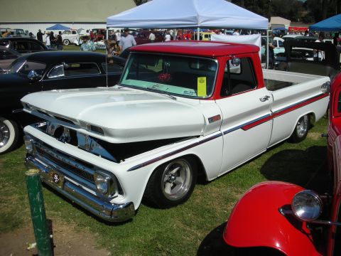 1998 Ford Crown Victoria - two-tone white-and-red Chevrolet fleetside pickup, lowered on chrome wheels, parked on grass at a car show.