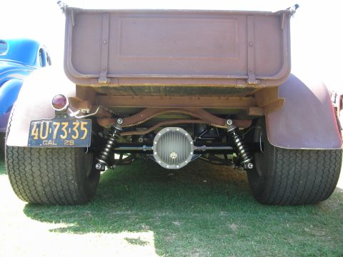 1998 Ford Crown Victoria - Rear of a brown roadster pickup with exposed coilover shocks, finned differential cover and a yellow plate reading 4U-73-35 CAL 29.