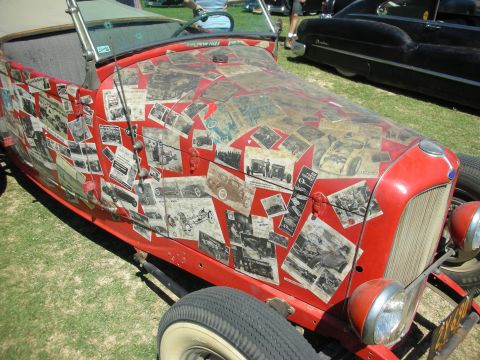 1998 Ford Crown Victoria - Side view of a red roadster whose hood and body are decoupaged with vintage black-and-white racing and hot-rod photographs.