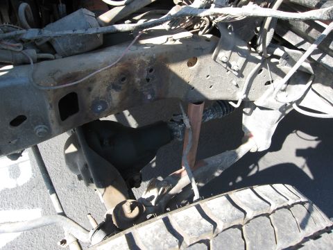 1986 Ford Bronco - Close-up of a vehicle's undercarriage, showing the frame, suspension, and a tire.