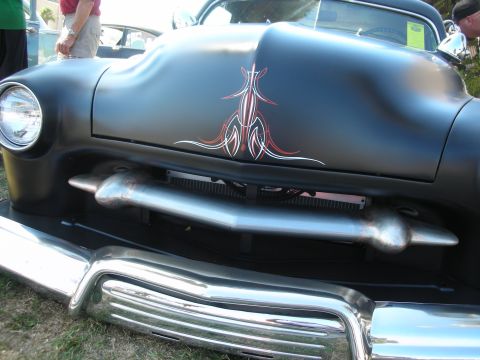 1998 Ford Crown Victoria - Close-up of a satin-black custom hood with ornate red-and-white pinstriping above a frenched chrome grille and bumper.