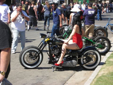 1998 Ford Crown Victoria - woman in red poses on a black bobber amid a crowd; a sign on a bike behind reads KEEP BACK 200 FT.