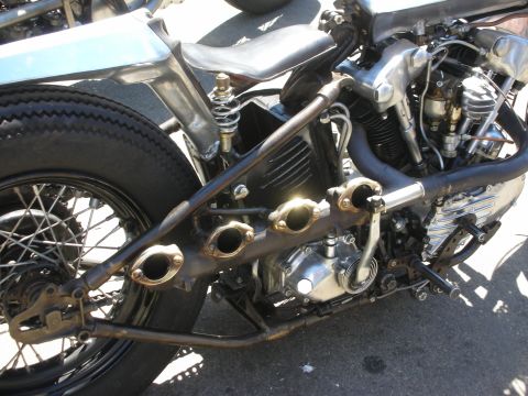1998 Ford Crown Victoria - Detailed close-up of a hardtail bobber's V-twin engine, oil tank, springs and short open exhaust headers in bare metal.