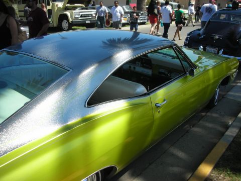 1998 Ford Crown Victoria - side profile of a lime-green metalflake custom coupe with a silver roof fade and chrome wheels, shot among a crowd at a car show.