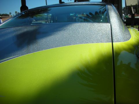 1998 Ford Crown Victoria - close-up of a custom car's body panel shows a striking fade from lime-green to silver metalflake paint sparkling in the sun.
