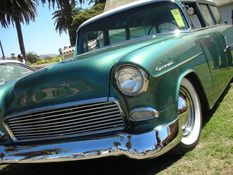 1998 Ford Crown Victoria - low-angle shot of a teal 1955 Chevrolet wagon shows its single headlight, chrome grille, Chevrolet hood script, and whitewall tire.