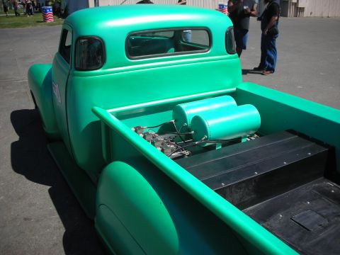 1998 Ford Crown Victoria - rear of a green chopped pickup reveals twin polished air tanks and air-suspension plumbing mounted in the truck bed.
