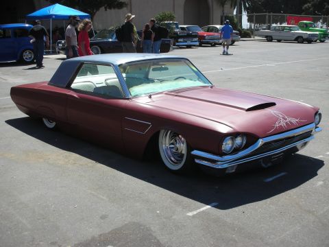 1998 Ford Crown Victoria - maroon slammed 1965 Ford Thunderbird coupe with hood scoop, pinstriping and whitewall tires at an outdoor car show.
