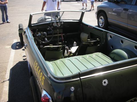 1998 Ford Crown Victoria - Looking into the open cockpit of an olive-green roadster, showing the steering wheel, dash gauges and a ribbed green rear deck.