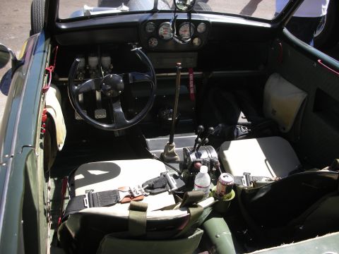 1998 Ford Crown Victoria - stripped roadster interior with bucket seats, a racing harness, floor shifter and a small gauge cluster on the dash.
