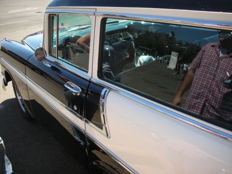 1998 Ford Crown Victoria - Side view detail of a black two-door station wagon's window and chrome trim, with the interior and a reflected bystander visible.