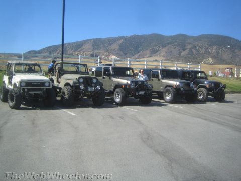1987 Suzuki Samurai - A group of off-road vehicles, including a Suzuki Samurai and multiple Jeeps, parked in a lot.