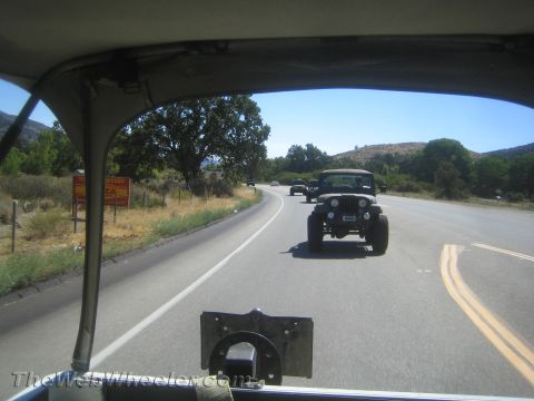 1987 Suzuki Samurai - A convoy of Jeep CJ-7s travels down a highway on a sunny day, seen from the perspective of the lead vehicle.