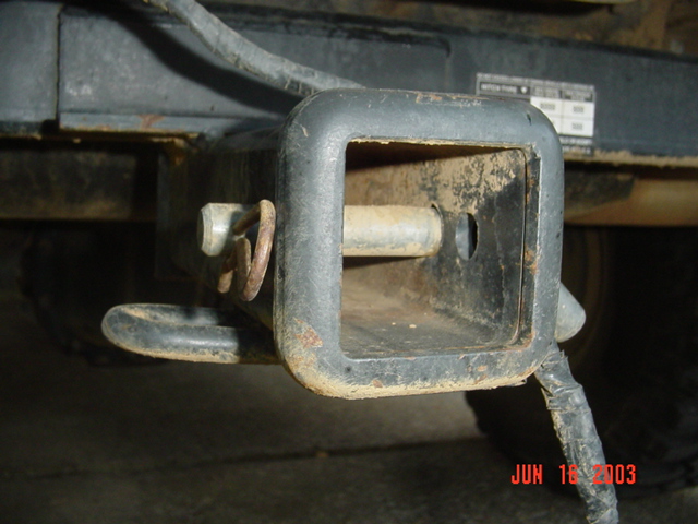 Close-up of a square receiver hitch with a pin and clip under the rear of a vehicle