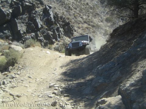 1987 Suzuki Samurai - A Jeep Wrangler navigates a challenging, dusty off-road trail with steep, rocky inclines.