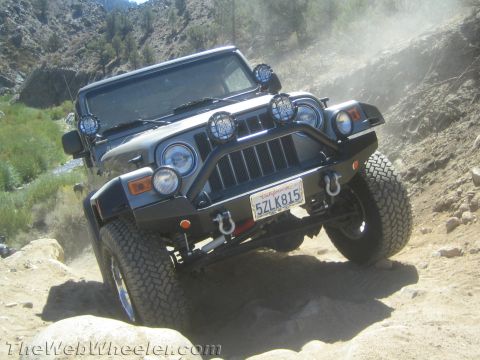1987 Suzuki Samurai - A gray Jeep Wrangler TJ navigates a rocky, dusty trail, its off-road modifications.
