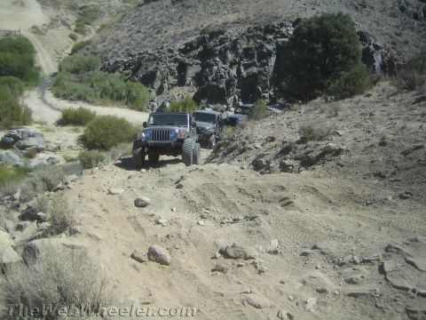 1987 Suzuki Samurai - Multiple Jeep Wranglers navigate a challenging off-road trail with steep inclines and rocky terrain.