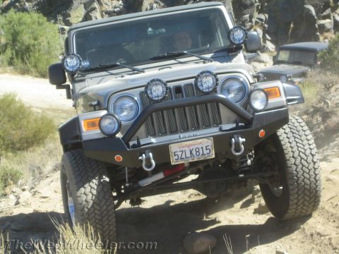 1987 Suzuki Samurai - A silver Jeep Wrangler TJ navigates a rocky trail, with a second vehicle visible behind it.