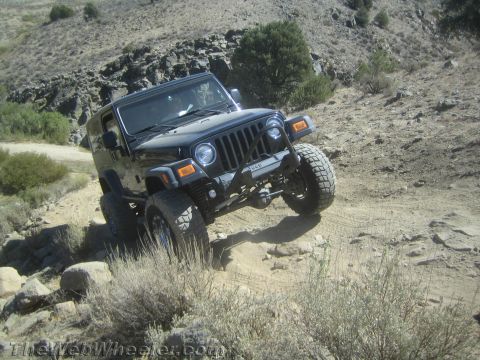 1987 Suzuki Samurai - Jeep Wrangler navigating a challenging off-road trail with rocky terrain.