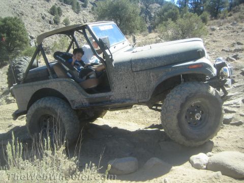1987 Suzuki Samurai - A Jeep CJ-7 navigates a rough, rocky terrain on an off-road trail.